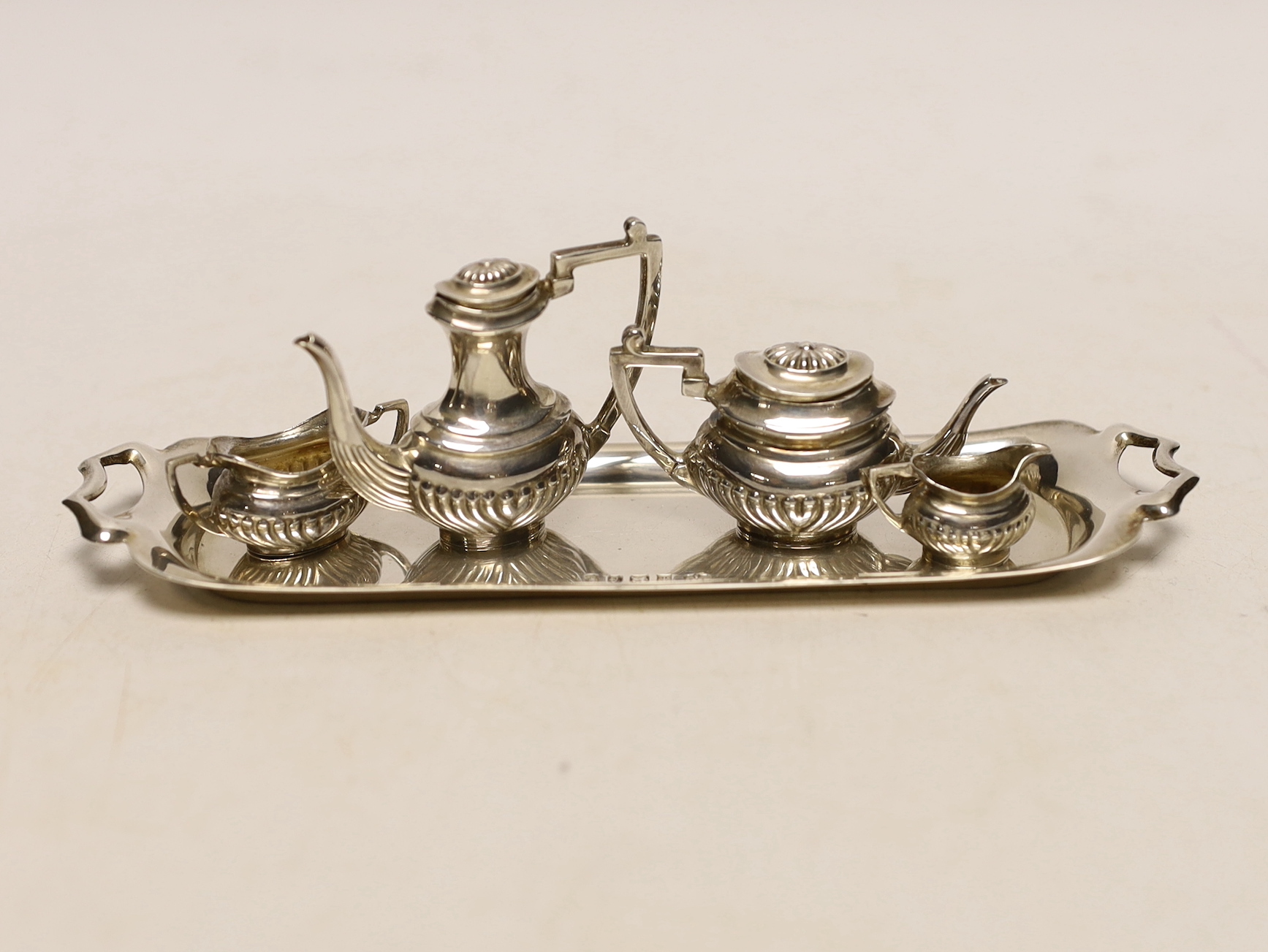 An Elizabeth II silver miniature four piece tea set and two handled tea tray, by Mappin & Webb, London, 1977, tray 14.9cm.